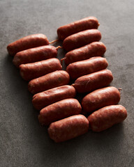 Mini pork sausages on grey concrete background, loft style. Raw and uncooked. 