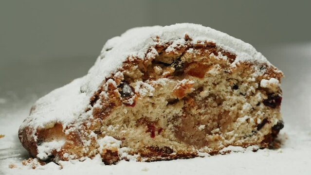 German Stollen bakery dessert close-up. Bun with spices, raisins, nuts and candied fruits and powdered sugar on top. Christmas desserts. Bakehouse
