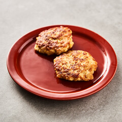 Single Golden Brown Chopped Chicken Cutlet or Patties with mozzarella cheese in red plate on concrete background.