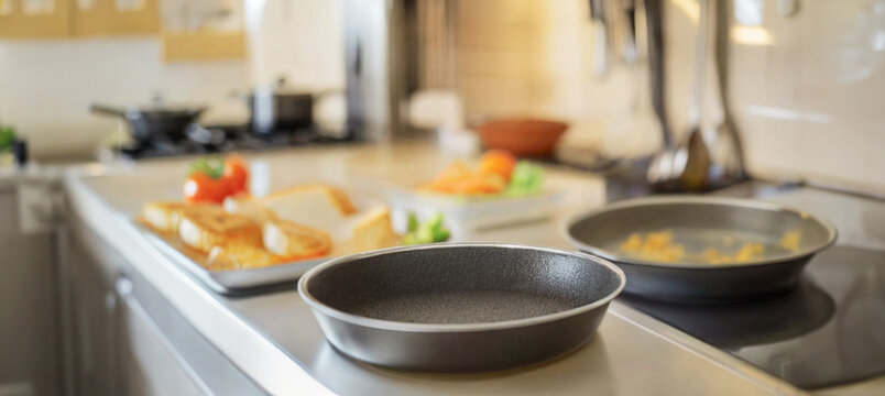 immagine ravvicinata di tegami da cucina in materiale antiaderente, sfondo ambiente cucina ampio e luminoso