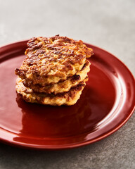 Single Golden Brown Chopped Chicken Cutlet or Patties with mozzarella cheese in red plate on concrete background.