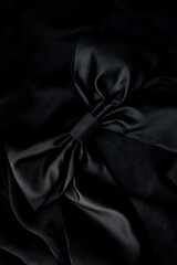 black bow, on a black background. Black background made of takini with a bow. silk fabric black...