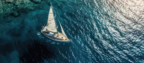 Zelfklevend Fotobehang Aerial drone ultra wide panoramic photo with copy space of beautiful sail boat with white sails cruising deep blue sea near Mediterranean destination port. Copy space image © Gular