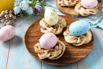 Sweet italian Easter bread rings from puff pastry and dyed eggs on a wooden blue tabletop.