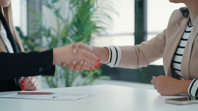 Video of attractive real-estate agent woman giving house keys to woman after signing agreement contract in the office.