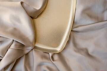 Folds of beige satin fabric and gold delivery, gold plate. Background for subject photography....