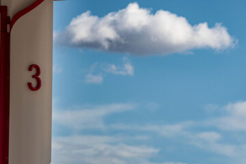Red color number three, blue sky with clouds. Terminal, heaven concept.