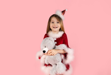 Christmas, teddy bear and happiness with a girl in studio with pink background, dressed in red...