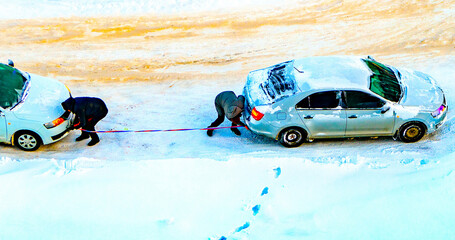 Drivers attach a tow rope to their cars to tow a faulty frozen automobile in the frosty...