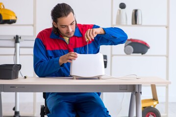 Young male contractor repairing toaster at workshop