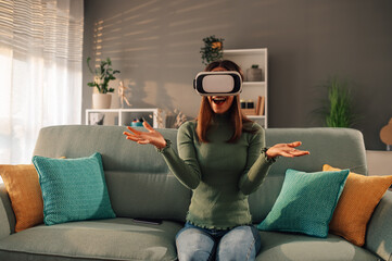 Woman using virtual reality headset at home and spreading hands