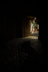 Blick durch einen Tunnel zu einer schwach beleuchteten Gasse in der Altstadt von Malcesine in...