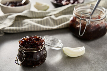 Two jars or preserves with Delicious French Appetizer Freshly Cooked Onion Confit. Concrete loft background. 