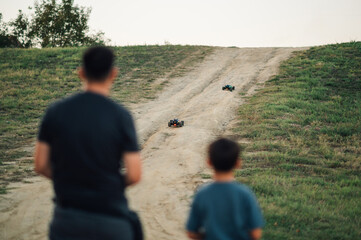 Toy car race between a young boy and his father in the countryside.