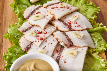 Salo on a wooden board with green salad, mustard and garlic, close-up, shallow depth of field