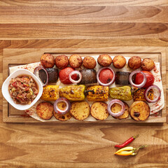 Fried vegetables on skewers on the wooden board - zucchini, eggplant, bell peppers, mushrooms, corn, red onion with spices, Top view flatlay