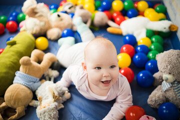 Fototapeta na wymiar Cute baby girl playing with colorful toys in the nursery at home