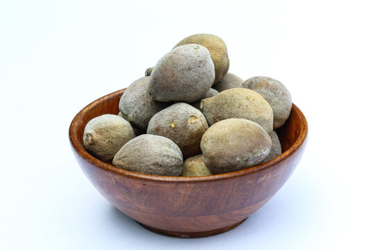 Terminalia bellirica in a wooden bowl on white background side view 