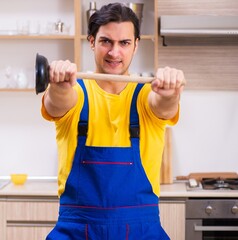 Young male contractor repairing tap at home