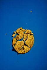 Golden and crusty potato chips on blue background. Minimalistic food photo. 