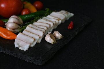pieces of lard, top view of bacon with red pepper on a black background,	
