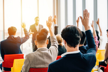 Businesspeople in a boardroom participate in a strategy session with a meeting and seminar. Questions spark active engagement with hands raised by colleagues and employees.