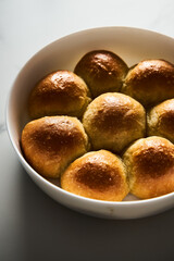 Burger Buns or mini buns in the round baking pan. Very soft Freshly Baked Homemade, buttered. White marble background. Minimalistic photo