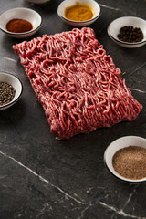 Raw and Fresh Minced Beef with spices for cooking on dark marble background. Minimalistic food...