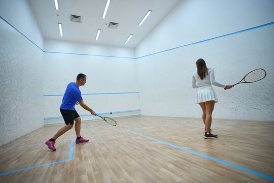 Energetic sportswoman practices refining hitting skills with squash man coach - Powered by Adobe