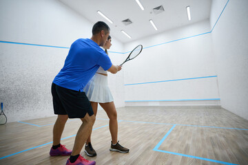 Woman refines hitting precision in squash lesson with man instructor