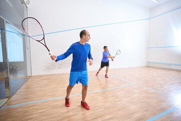 Sporty men playing squash showing their athletic skills