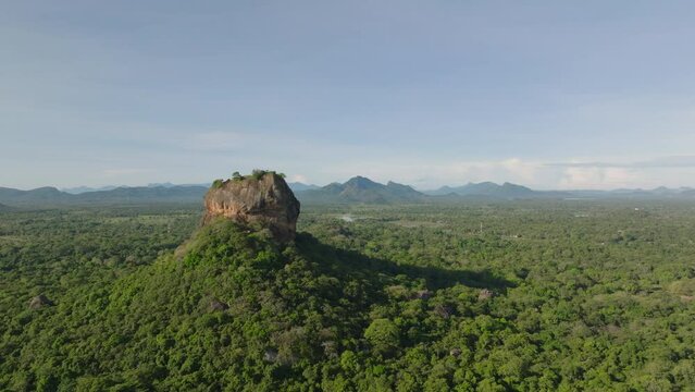 Aerial view of famous Lions Rock rising above vast forest in tropical landscape. Popular tourist destination with ruins of ancient palace. Sigiriya, Sri Lanka