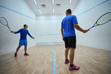 Sporty men playing squash showing their athletic skills on court