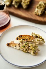Golden Biscotti or Cantuccini on white plate on the white marble background.Traditional Sweet Italian cookies, two times baking, with nuts and dried cranberries served with filter coffee