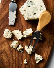 Gorgonzola cheese on wood board with cheese knife and fork. On white marble background