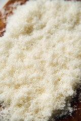 Grated parmesan cheese on a wooden board. White, bright and clean background.