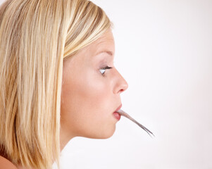 Woman, surprise and eating a fish in mouth with strange food or tail on lips in white background or mockup. Crazy, diet and person with weird seafood, cuisine and disgust for taste of tuna or salmon