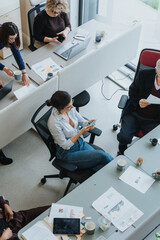 High-angle shot of a diverse group of coworkers engaged in a collaborative work setting in a...