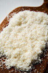 Grated parmesan cheese on a wooden board. White, bright and clean background.