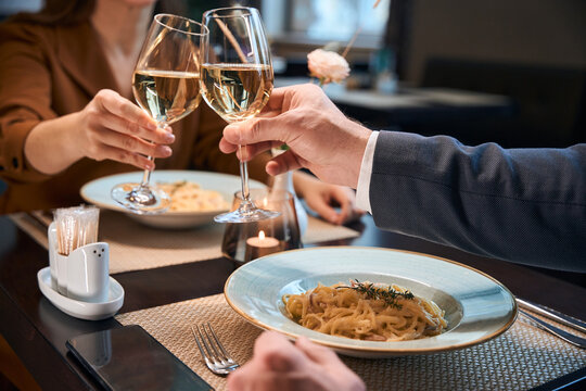 Partial image of couple toasting wine from glasses in hotel restaurant