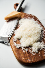 Grated parmesan cheese on a wooden board. White, bright and clean background.