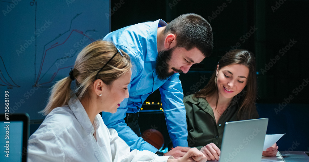 Wall mural caucasian man boss of company controlling and checking work of two beautiful female office workers. 