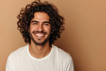 Obraz premium Smiling man with curly hair and white T-shirt on a beige background