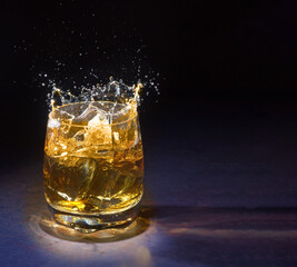 Glass of whisky on ice served on a rustic wooden counter in a pub