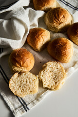Burger Buns or mini buns on white marble background and kitchen towel. Very soft Freshly Baked Homemade, buttered. Minimalistic photo. 