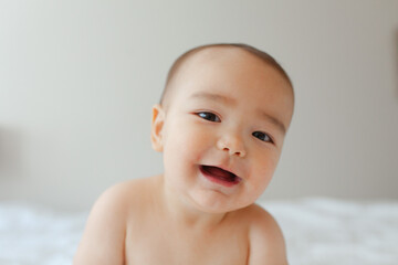 Naked baby sitting on a bed