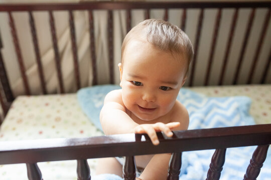 baby in a crib smiling no shirt with a diaper