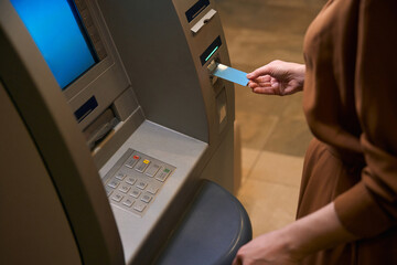 Cropped image of woman insert credit card in ATM in hotel lobby
