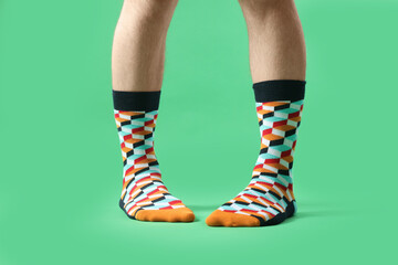 Man in stylish colorful socks on light green background, closeup