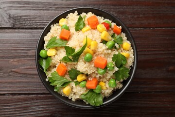 Tasty quinoa porridge with vegetables in bowl on wooden table, top view